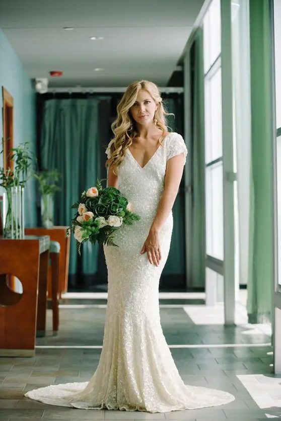 a white sequin V cut wedding dress with short sleeves and a small train is a chic and timeless idea