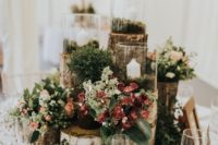 a woodland wedding centerpiece of tree stumps, moss, succulents, greenery, blooms and candles and little mushrooms