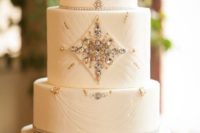 an art deco wedding cake with beautiful embellishments and a feather on top is a gorgeous sparkling idea