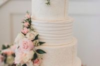 an elegant vintage wedding cake with textural tiiers and pink and white blooms plus greenery and beads of sugar