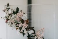 an ultra-modern white mesh backdrop with blush and white blooms, dark foliage and magnolia leaves