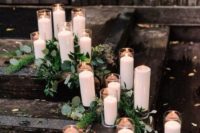 decorate your wedding space with pillar candles in white and greenery for a chic look