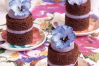 individual naked chocolate wedding cakes with blueberry cream and blooms on top