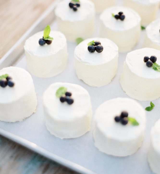 individual white mini cakes topped wiht mint and blueberries are delicious, fresh and tasty, perfect for a modern or rustic wedding