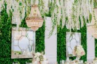 vintage mirrors with frames and a greenery wall plus a huge white bloom hanging over the reception are a refined idea