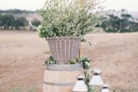a barrel with a basket with olive branches, candle lanterns is a nice decoration for a wedding ceremony space
