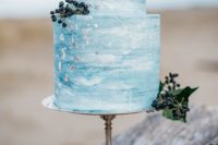 a blue watercolor wedding cake with silver leaf and privet berries is a nice idea for a beach wedding