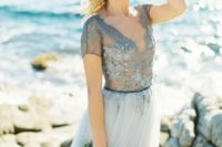 a blue wedding dress with a lace embellished bodice with short sleeves and a light blue pleated skirt for a beach bride