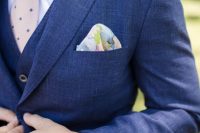 a bold blue three-piece suit, a white shirt, a blush printed tie, a floral handkerchief are an amazing combo for an elegant look at the wedding