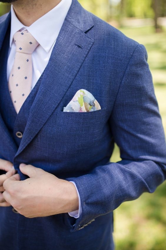 A bold blue three piece suit, a white shirt, a blush printed tie, a floral handkerchief are an amazing combo for an elegant look at the wedding