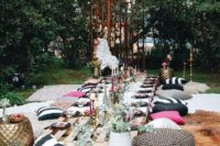 a bright and fun bridal shower picnic setting with colorful pillows, candles, greenery, a pallet table and a creative backdrop