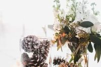 a centerpiece with some white blooms, snowy pinecones in a jar and a candle