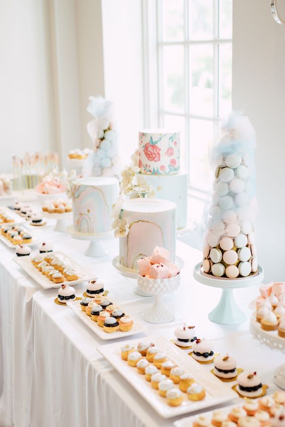 a chic pastel dessert table with delicious and exquisite sweets, a macaron tower and painted cakes