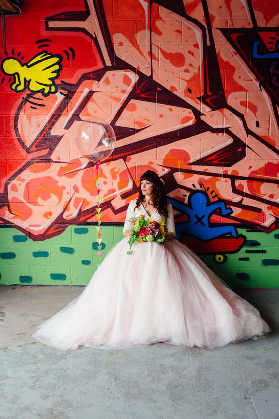 a colorful graffiti wall create a bold contrast to the neutral and romantic bridal look making her stand out a lot
