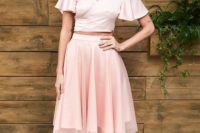 a cool ensemble of a pink silk crop top with bell sleeves and a V-neckline plus a knee pleated skirt and platform shoes