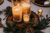 a cozy woodland wedding centerpiece of evergreens, a tree slice, candles and a tree slice table number is lovely