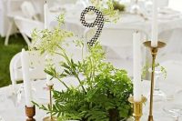 a glass bowl with greenery and herbs and a black and white table number for a woodland wedding