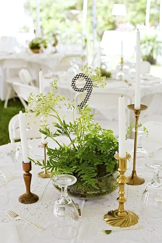 a glass bowl with greenery and herbs and a black and white table number for a woodland wedding