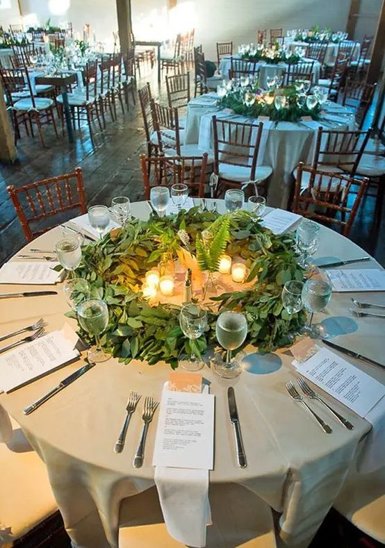 A greenery table centerpiece with eucalyptus, ferns and candles is a unique wreath like piece
