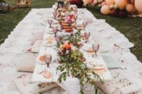 a lovely summer bridal shower picnic with a low table, printed pillows and blankets, blooms and greenery and flower topped cakes