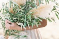 a lush wedding bouquet of pampas grass and olive branches is a creative and bold idea for a natural bride