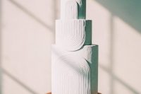 a modern white wedding cake with textural detailing is a chic and refined idea for a contemporary wedding