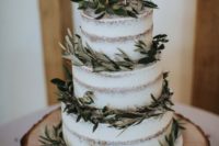 a naked wedding cake wrapped up with olive greenery and with a calligraphy topper for a rustic wedding