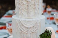 a neutral boho wedding cake with macrame patterns and succulents and greenery is very bold and cool
