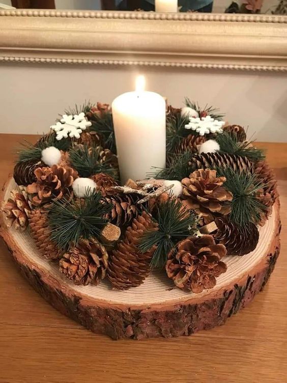 a pretty winter woodland wedding centerpiece of a tree slice, pinecones, evergreens, snowflakes and a pillar candle