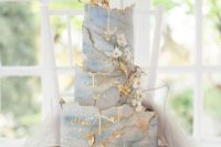 a refined blue and white marble wedding cake with a gold edge and sugar blooms and gold leaves for a formal wedding