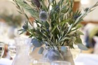 a simple wedding centerpiece of olive greenery, thistles allium, thistles and some dried herbs for a natural wedding