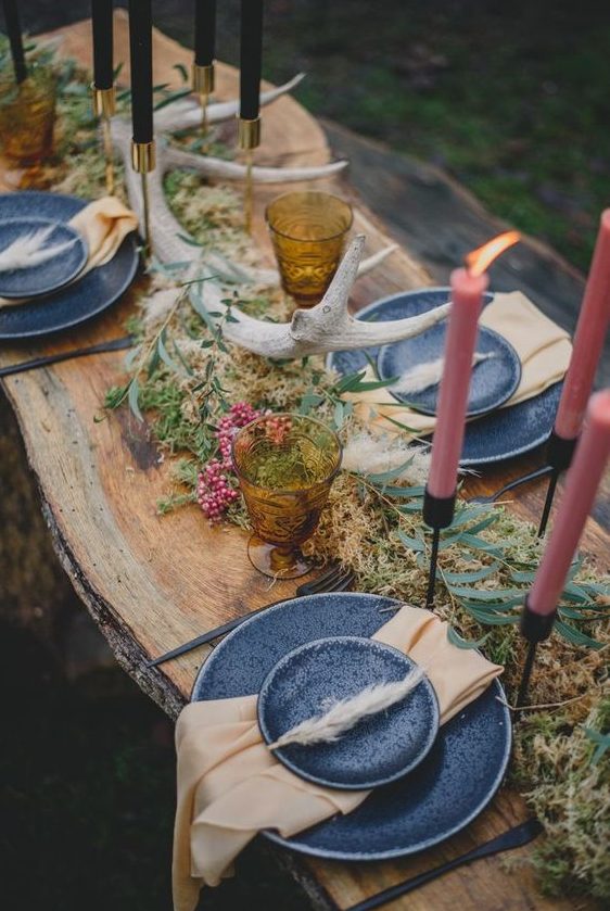 a simple woodland wedding table with dried herbs, berries, antlers, colored candles and grey plates
