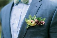 a stylish woodland groom’s look with a grey suit, a light blue shirt, a green bow tie shaped as leaves, a burgundy and yellow pocket square with blooms and berries