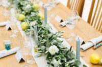 a summer wedding tablescape with eucalyptus, olive, white blooms, lemons and grey candles for a bright look