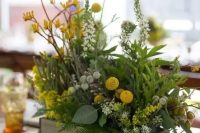 a summer woodland centerpiece with ferns, berries, billy balls, yellow flowers and various greenery