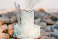a textural white and turquoise wedding cake decorated with pearls, corals and a seashell on top