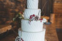 a textural white wedding cake with snowy pinecones, berries and twigs is a lovely rustic dessert idea