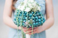 a unique beach wedding bouquet made of blue seashells, some white blooms and cascading greenery