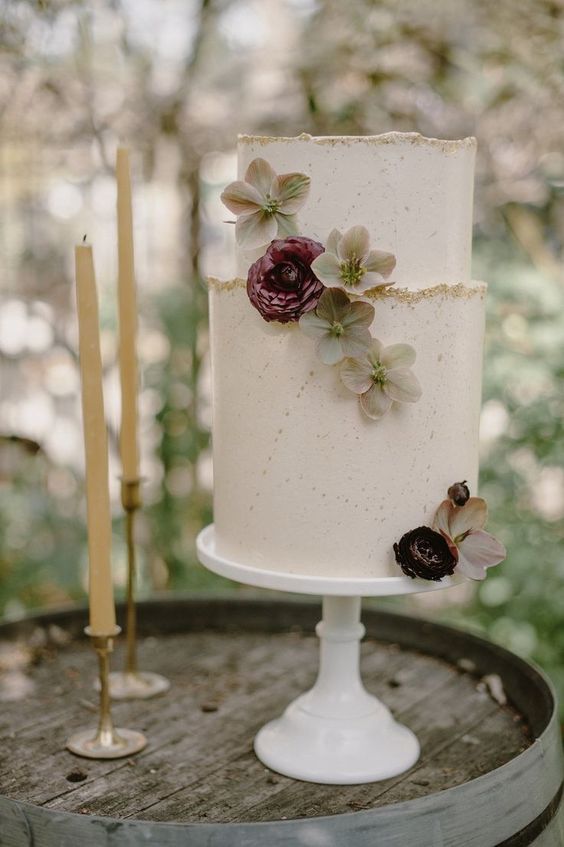 a white textural wedding cake with a gold glitter edge, fresh blooms is an elegant and romantic piece