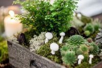 a woodland centerpiece in a crate with moss, succulents, greenery and faux mushrooms
