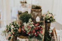 a woodland wedding centerpiece of tree stumps, moss, succulents, greenery, blooms and candles and little mushrooms