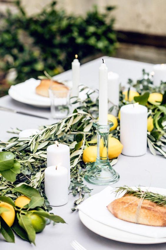 an Italian summer bridal shower table with candles, greenery, lemons and limes plus bread on plates