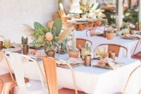 an outdoor summer bridal shower setting with copper chairs, cactus and pampas grass centerpieces and terracotta pots