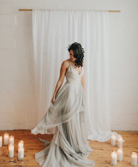 a beautiful dove grey wedding dress with a plunging neckline, spaghetti straps and a layered skirt with a train