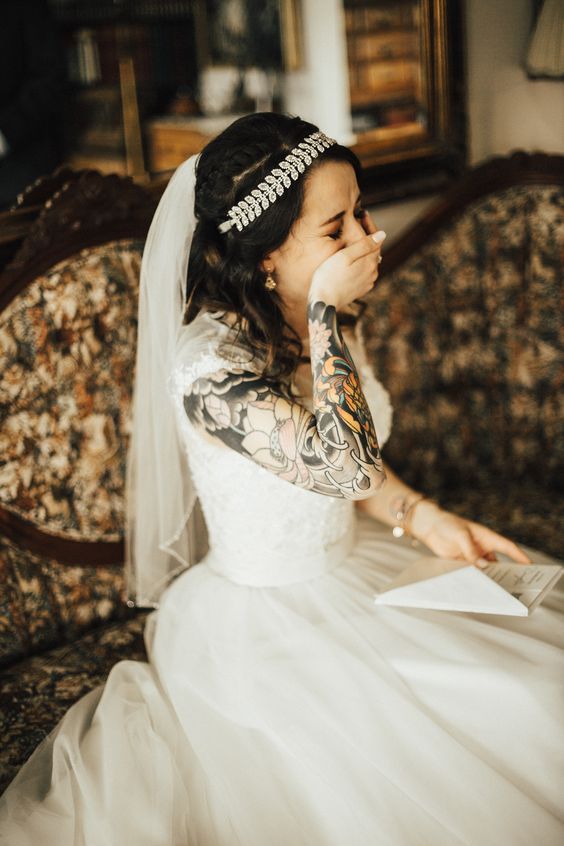 a beautiful lace embellished wedding ballgown with cap sleeves and a bold tattoo sleeve on the right arm that is beautifully shown off