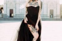 a black strapless wedding dress that show off the bride’s tattoos on the neck, chest, shoulders and arms plus on the leg