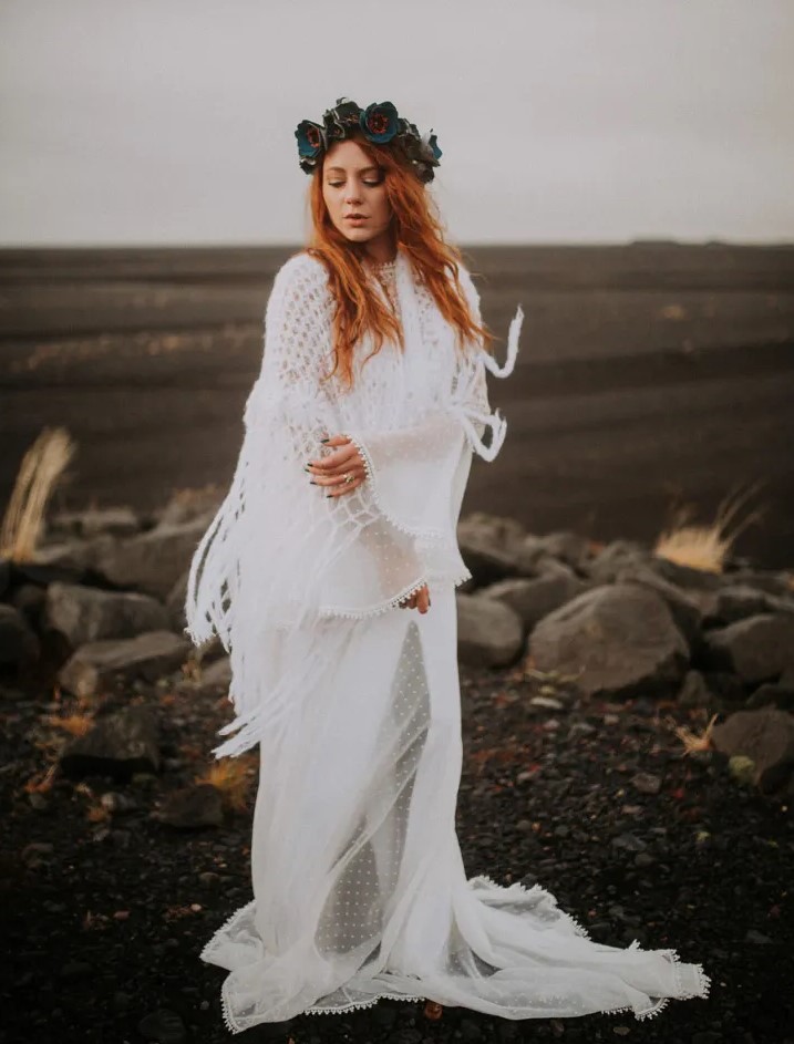 a boho Icelandic bride wearing a neutral polka dot wedding dress with bell sleeves and a crochet cover up