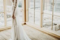 a boho lace bridal separate with a crop top with long sleeves and a skirt with a train plus a braided updo and statement earrings