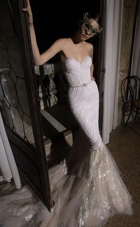 a breathtaking embellished strapless mermaid wedding dress with a layered tail and a mask