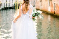 a breezy bridal look with a neutral wedding dress with a tulle skirt and an open back pictured on a bank in Venice